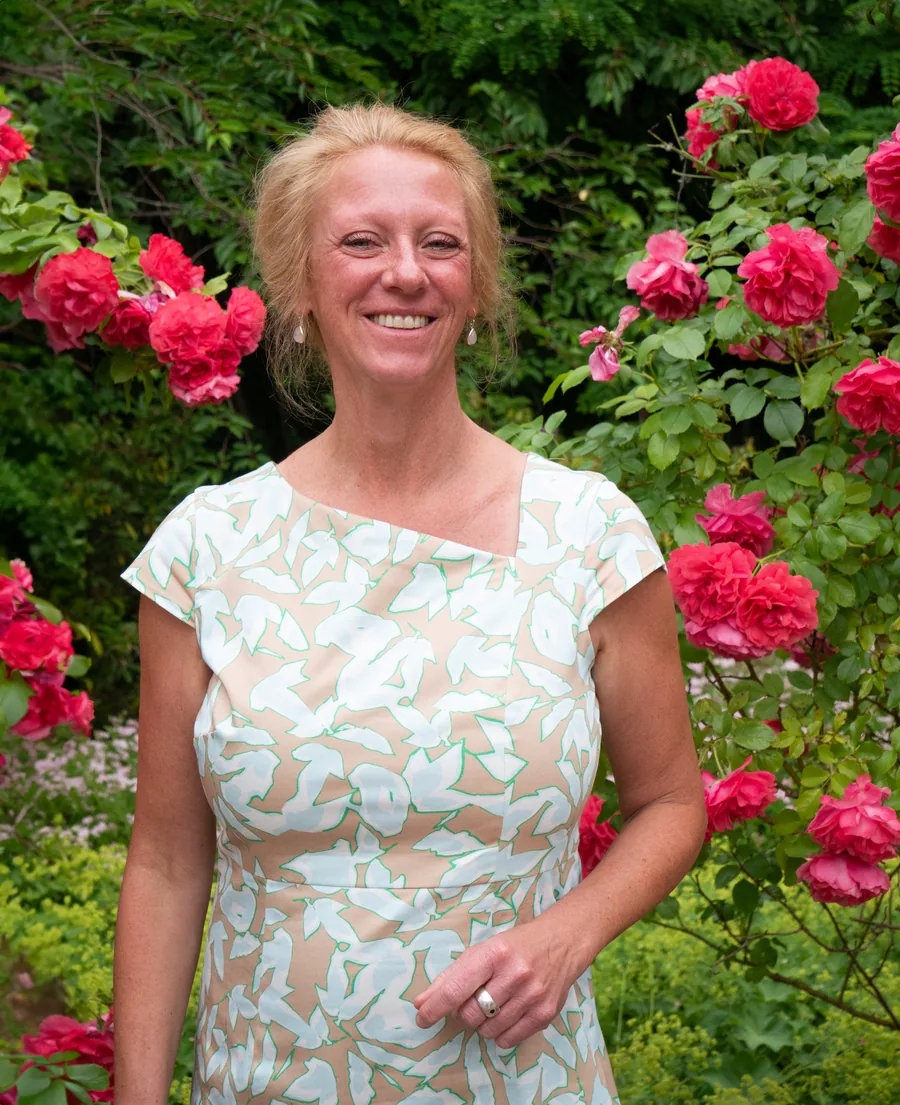 Dörthe Bräuner, Ansprechpartnerin der Selbsthilfegruppe Wedel, im Porträt vor einem blühenden Rosenstrauch.